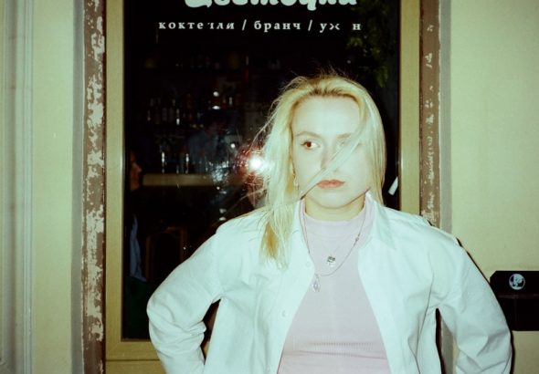 A woman stands in front of a window.