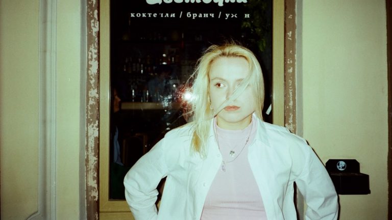 A woman stands in front of a window.